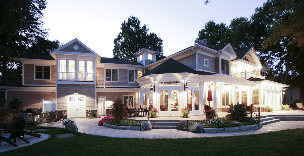 Photo of an expansive traditional two-storey beige house exterior in Other with wood siding and a shingle roof.