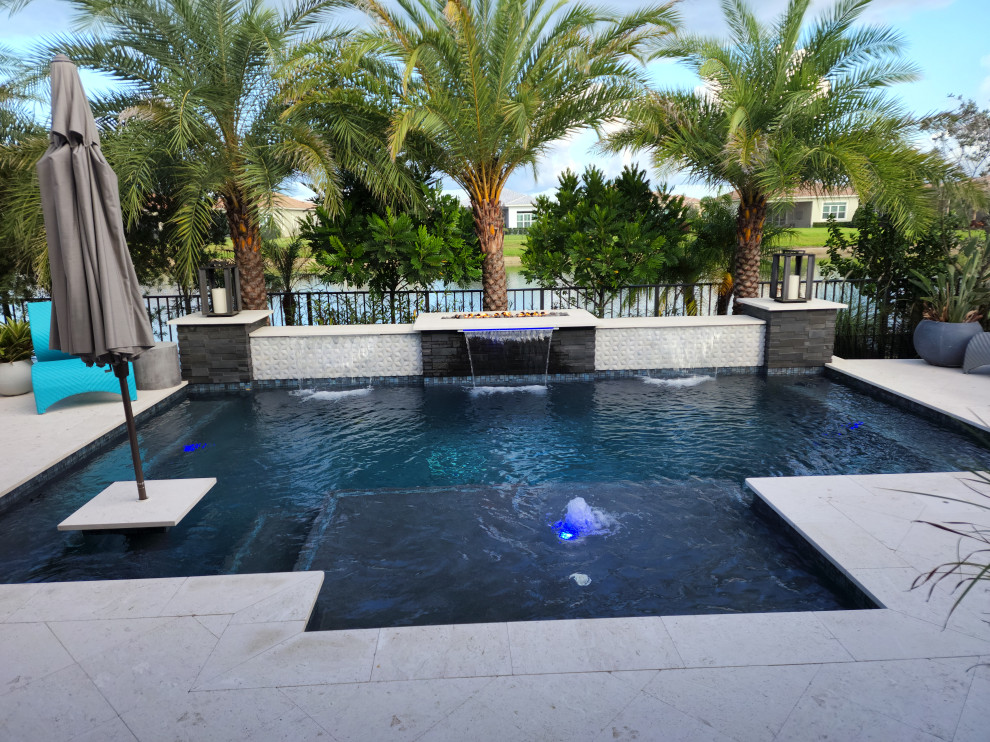 Foto de piscina actual en patio trasero con adoquines de piedra natural