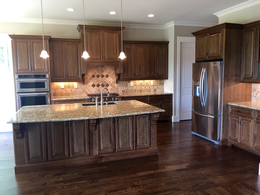 Design ideas for a large transitional l-shaped kitchen in Atlanta with an undermount sink, raised-panel cabinets, medium wood cabinets, granite benchtops, beige splashback, mosaic tile splashback, stainless steel appliances, dark hardwood floors and with island.