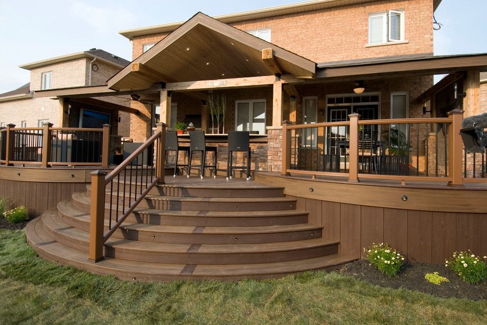 Photo of a large country backyard deck in Toronto with an outdoor kitchen and a roof extension.