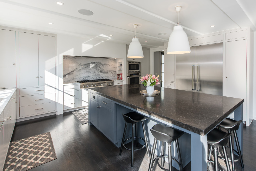 Large contemporary u-shaped open plan kitchen in DC Metro with an undermount sink, flat-panel cabinets, white cabinets, limestone benchtops, grey splashback, marble splashback, stainless steel appliances, dark hardwood floors, with island, black floor and black benchtop.