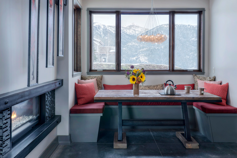 Mountain style concrete floor and gray floor dining room photo with gray walls, a two-sided fireplace and a metal fireplace