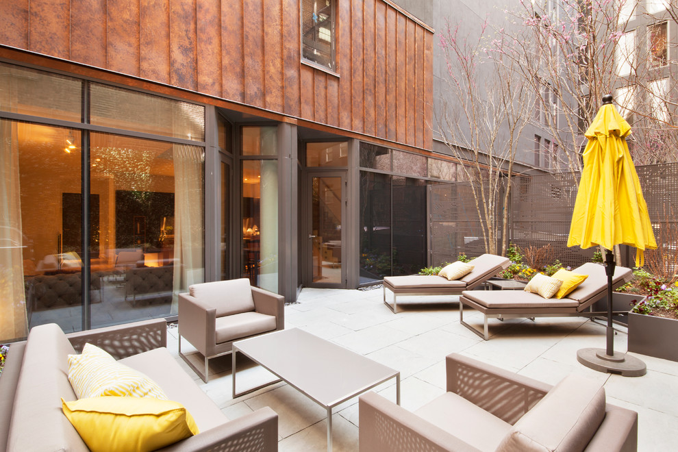 Inspiration for a mid-sized contemporary backyard patio in New York with natural stone pavers and no cover.