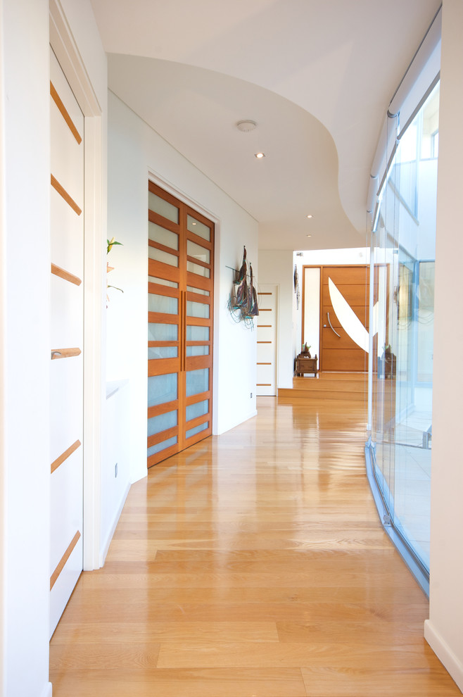 Contemporary hallway in Sunshine Coast with white walls and light hardwood floors.