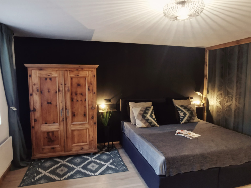 Идея дизайна: гостевая спальня среднего размера, (комната для гостей) в стиле шебби-шик с черными стенами, полом из винила, печью-буржуйкой, коричневым полом и обоями на стенах
