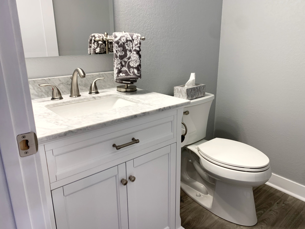 Photo of a classic cloakroom in Milwaukee with recessed-panel cabinets, white cabinets, a two-piece toilet, grey walls and multi-coloured worktops.