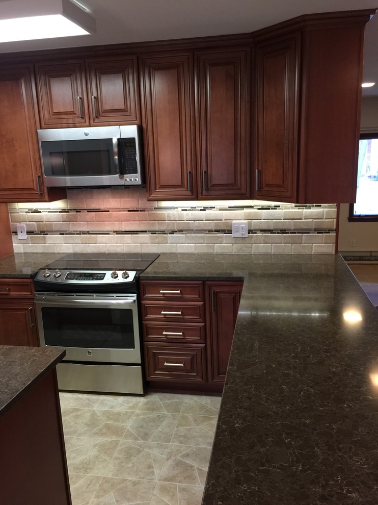 Photo of a small traditional l-shaped eat-in kitchen in Boston with an undermount sink, raised-panel cabinets, dark wood cabinets, quartz benchtops, beige splashback, stone tile splashback, stainless steel appliances, vinyl floors and with island.