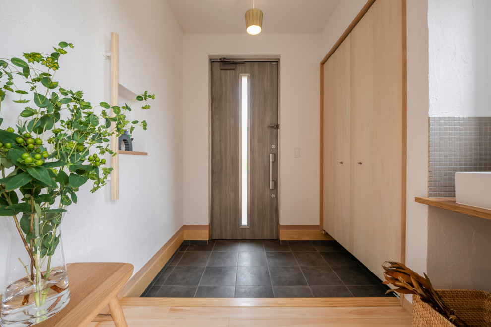 Foto de entrada minimalista con paredes blancas, suelo de madera clara, puerta simple y puerta gris