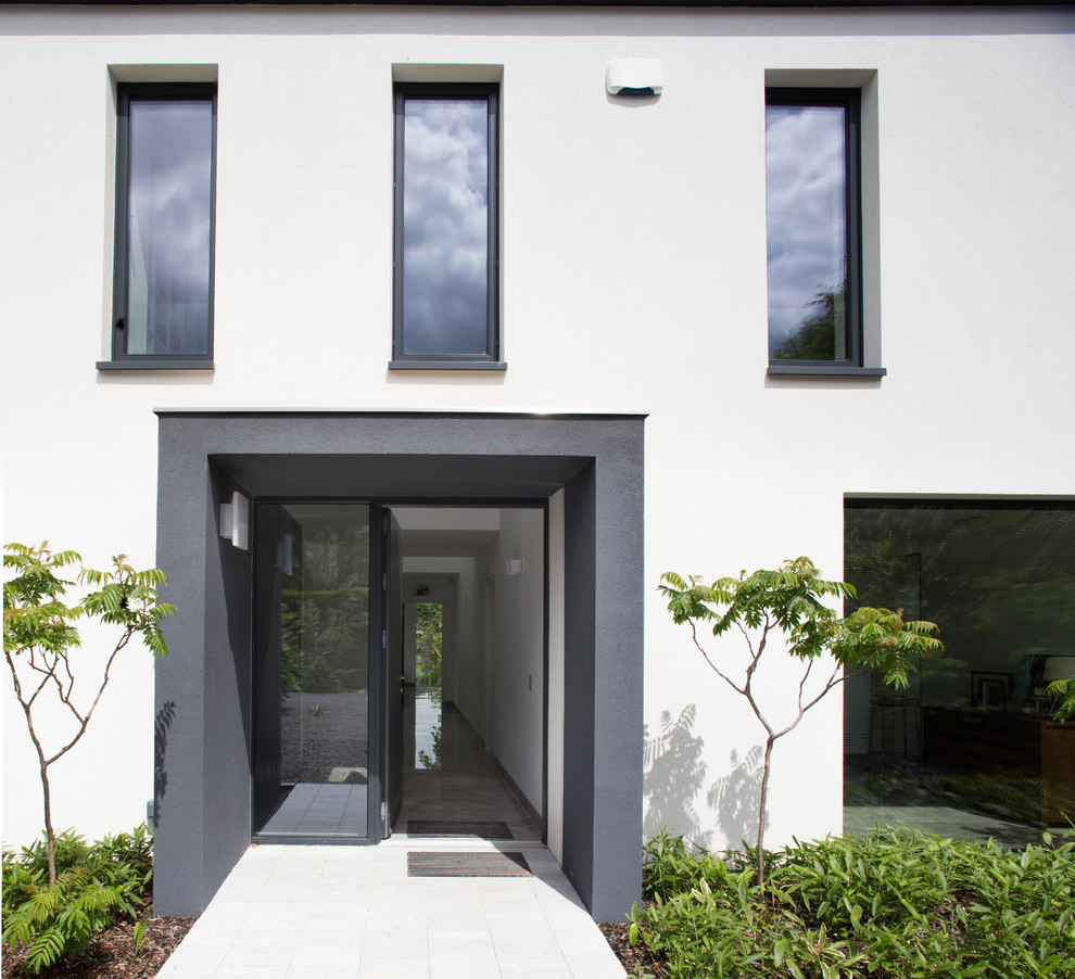 This is an example of a mid-sized contemporary front door in Dublin with white walls, granite floors, a single front door, a gray front door and white floor.