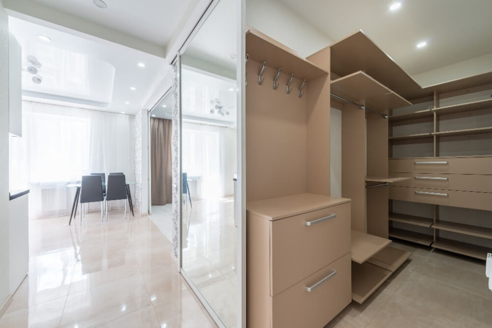 Inspiration for a mid-sized contemporary gender-neutral walk-in wardrobe in Moscow with flat-panel cabinets, beige cabinets, ceramic floors and beige floor.