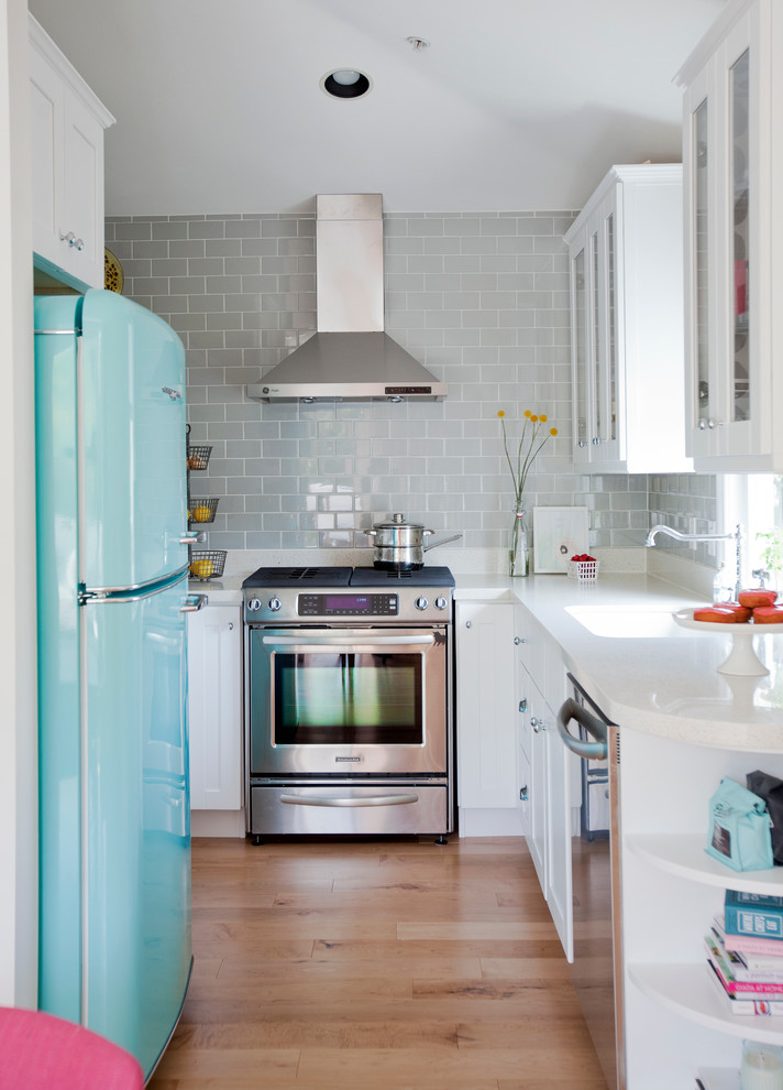 This is an example of an eclectic u-shaped kitchen in Vancouver with glass-front cabinets, white cabinets, grey splashback, subway tile splashback and coloured appliances.