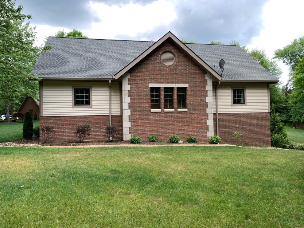 This is an example of a traditional brick beige house exterior in Cleveland with a gable roof and a shingle roof.