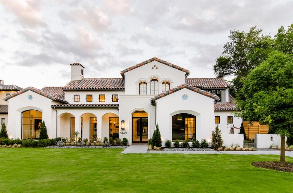 This is an example of a large mediterranean two-storey stucco white house exterior in Austin with a gable roof and a tile roof.