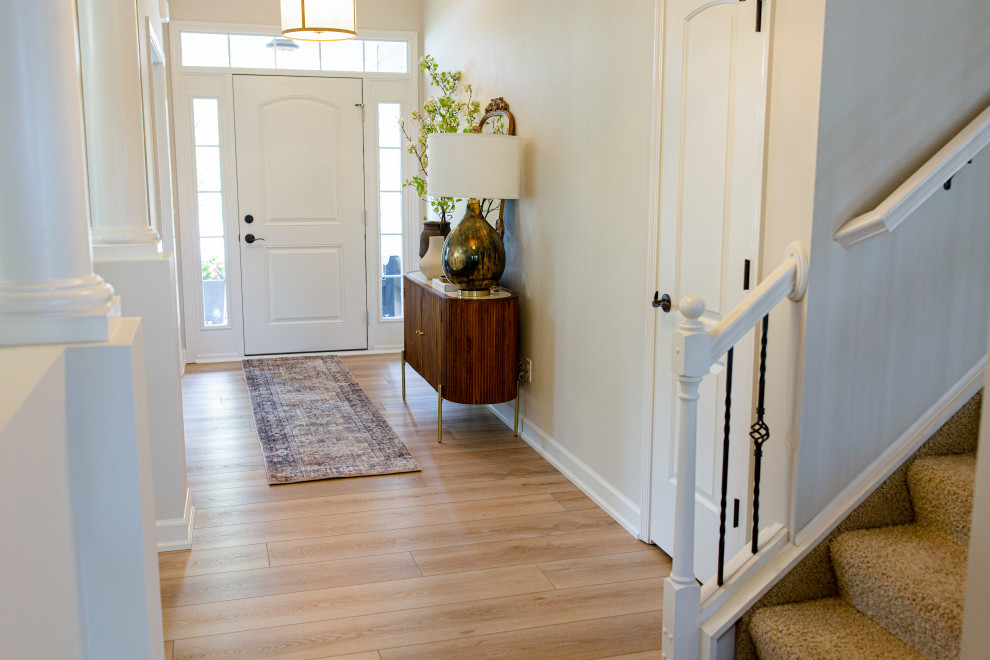 Photo of an expansive mediterranean front door in Indianapolis with white walls, vinyl flooring, a single front door, a white front door, beige floors and a vaulted ceiling.