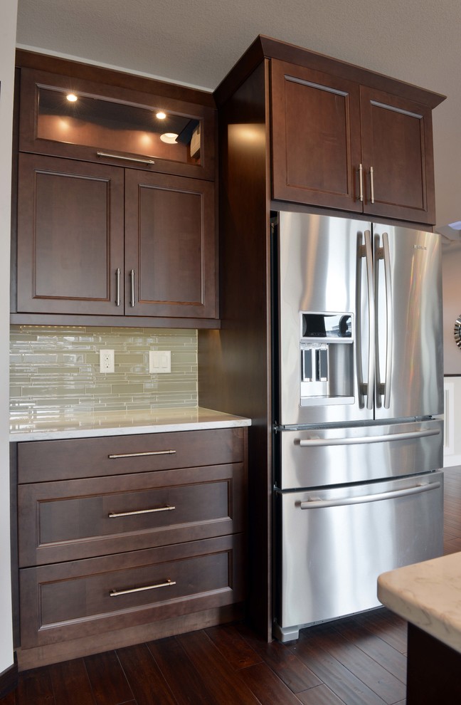 Inspiration for a large transitional l-shaped dark wood floor and brown floor eat-in kitchen remodel with an undermount sink, flat-panel cabinets, dark wood cabinets, quartz countertops, stainless steel appliances, an island, gray backsplash and glass sheet backsplash