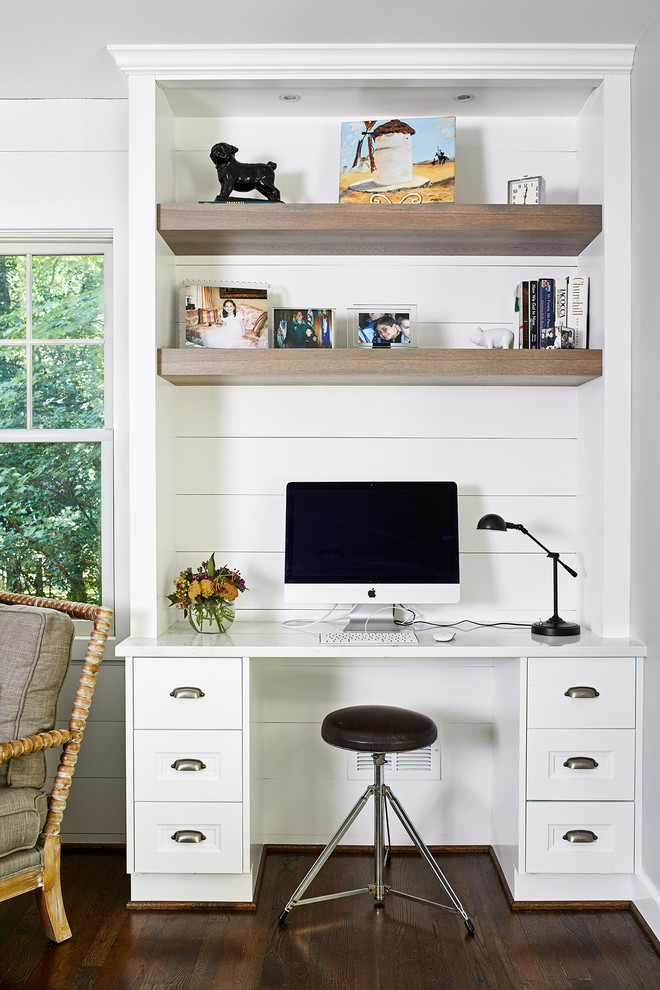 Photo of a country home office in DC Metro with white walls, dark hardwood floors, a built-in desk and brown floor.