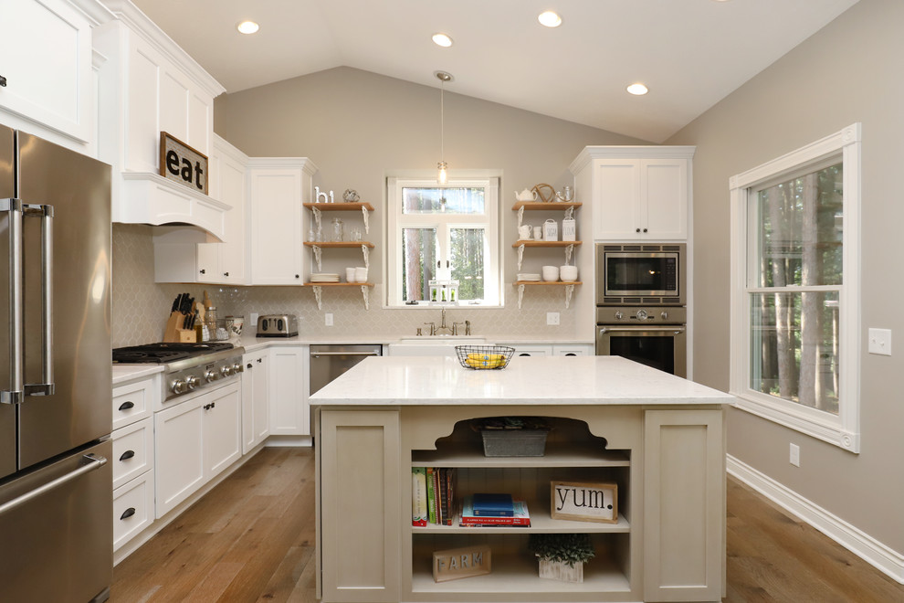 Inspiration for a mid-sized cottage l-shaped light wood floor and brown floor eat-in kitchen remodel in Grand Rapids with a farmhouse sink, shaker cabinets, white cabinets, quartz countertops, gray backsplash, ceramic backsplash, stainless steel appliances and an island