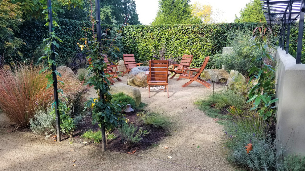 Mediterraner Garten im Sommer, hinter dem Haus mit Feuerstelle, direkter Sonneneinstrahlung und Granitsplitt in Seattle