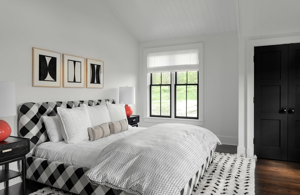 This is an example of a large country guest bedroom in New York with white walls, dark hardwood floors and brown floor.