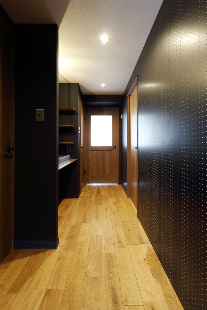 Photo of a mid-sized modern hallway in Tokyo with black walls, medium hardwood floors and brown floor.
