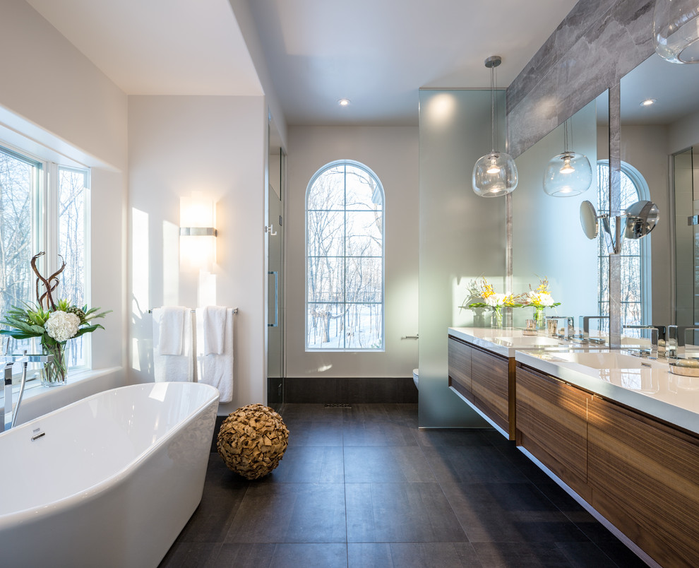 Inspiration for a large contemporary master bathroom in Ottawa with flat-panel cabinets, medium wood cabinets, a freestanding tub, an alcove shower, gray tile, porcelain tile, white walls and porcelain floors.