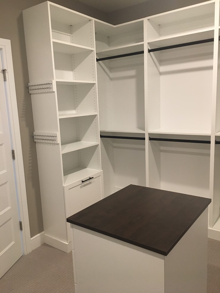 Design ideas for a mid-sized traditional gender-neutral walk-in wardrobe in New York with shaker cabinets, white cabinets and carpet.
