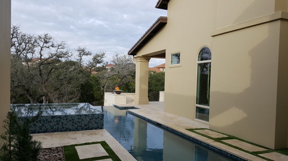 Large minimalist backyard stamped concrete and rectangular infinity hot tub photo in Austin