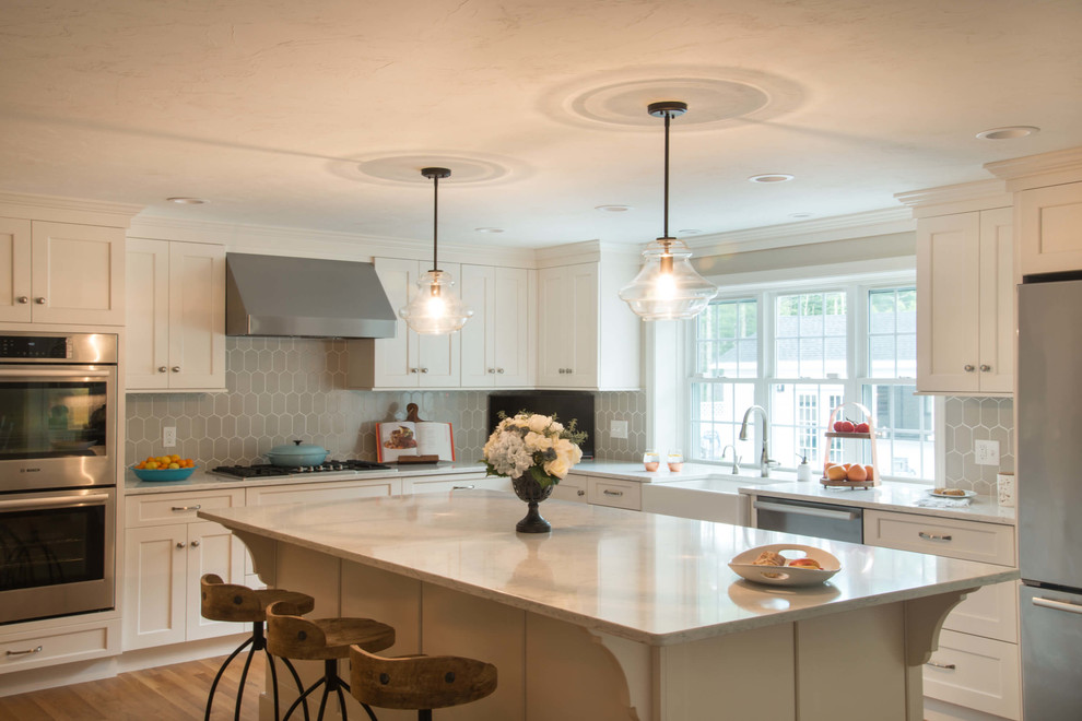 Example of a transitional l-shaped eat-in kitchen design in Providence with a farmhouse sink, quartzite countertops, ceramic backsplash, stainless steel appliances and an island