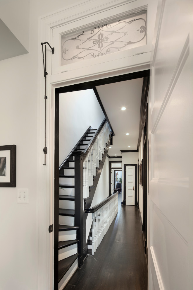 Immagine di un ingresso o corridoio boho chic di medie dimensioni con pareti bianche, parquet scuro e pavimento nero