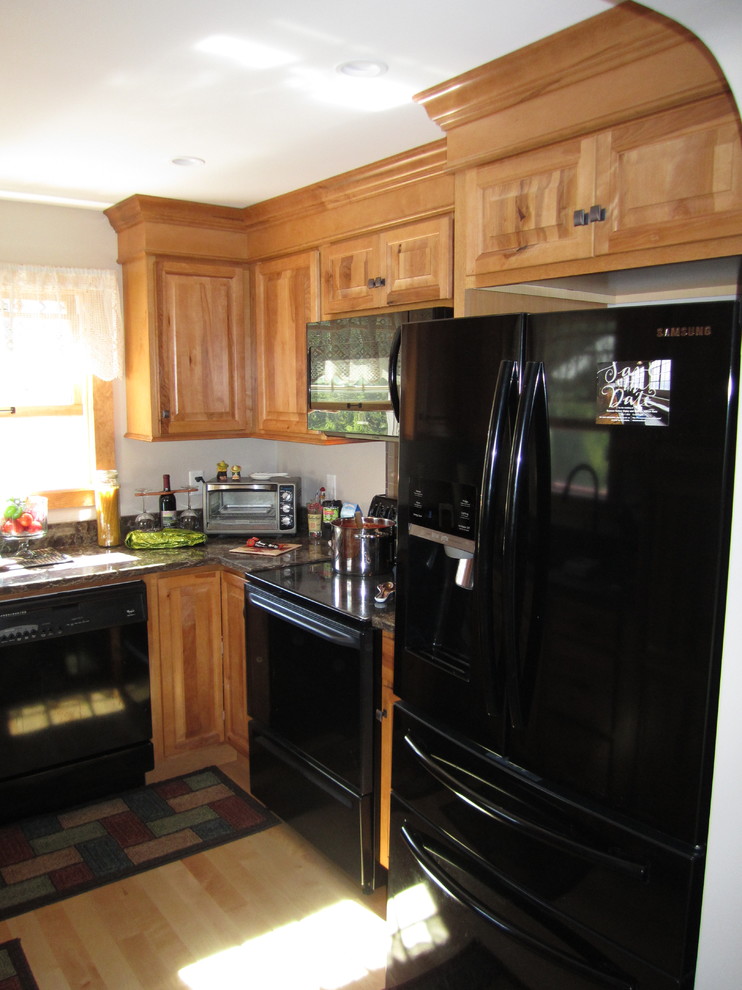 This is an example of a mid-sized country u-shaped separate kitchen in Boston with raised-panel cabinets, light wood cabinets, black appliances, no island, a single-bowl sink and quartz benchtops.