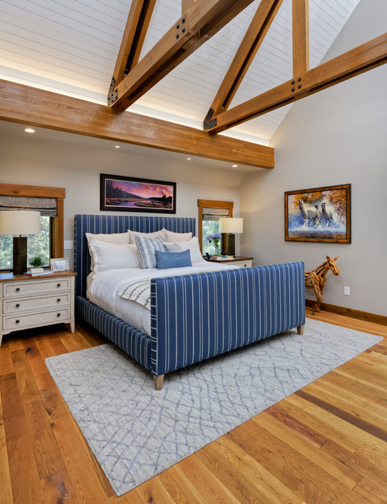 Ejemplo de dormitorio principal rural de tamaño medio con paredes beige, suelo de madera en tonos medios, todas las chimeneas y marco de chimenea de metal