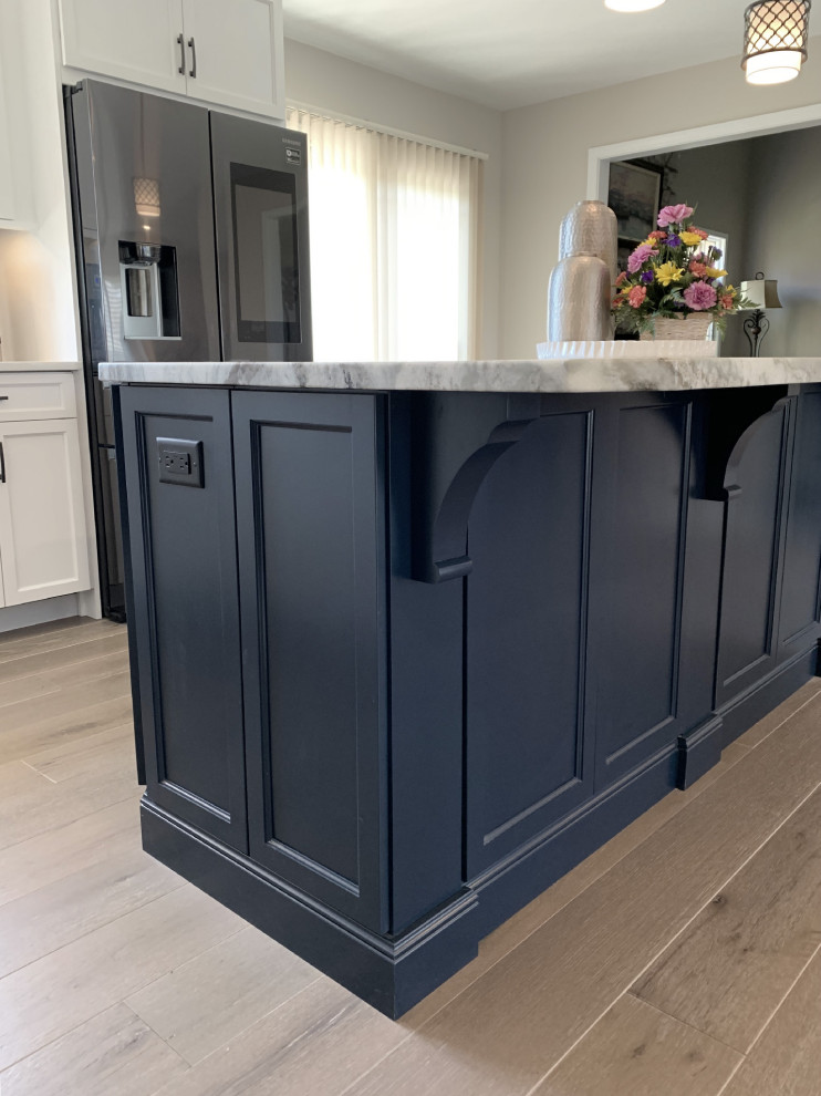 Example of a large transitional l-shaped vinyl floor and gray floor eat-in kitchen design with an undermount sink, recessed-panel cabinets, white cabinets, quartz countertops, gray backsplash, ceramic backsplash, stainless steel appliances, an island and white countertops