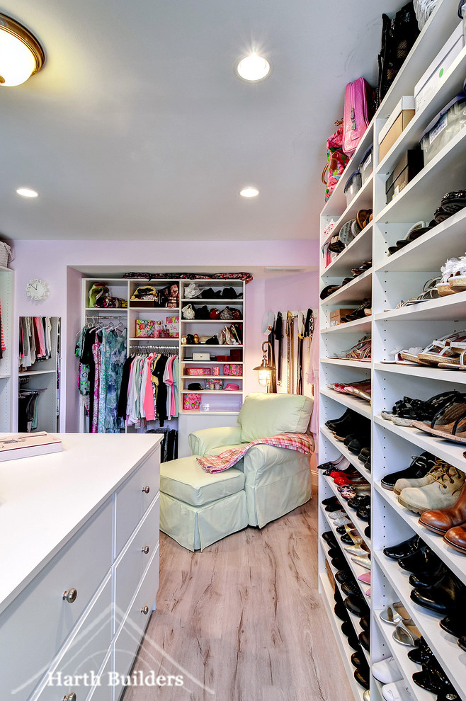This is an example of a large transitional women's walk-in wardrobe in Philadelphia with flat-panel cabinets, white cabinets and vinyl floors.