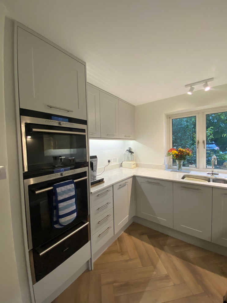Mittelgroße Moderne Küche mit hellem Holzboden und braunem Boden in London