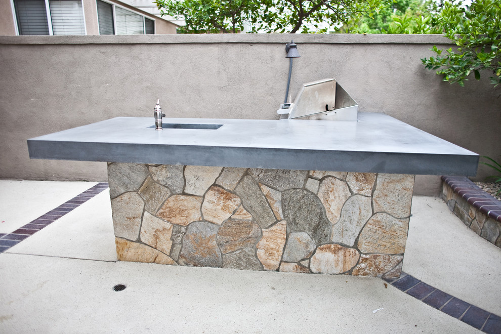 This is an example of a mid-sized backyard patio in Orange County with an outdoor kitchen, concrete slab and no cover.