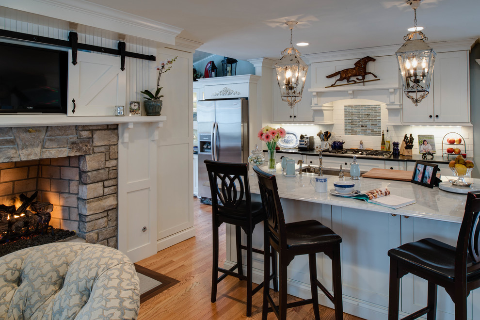 This is an example of a traditional single-wall eat-in kitchen in Detroit with an undermount sink, shaker cabinets, white cabinets, granite benchtops, white splashback, glass tile splashback and stainless steel appliances.