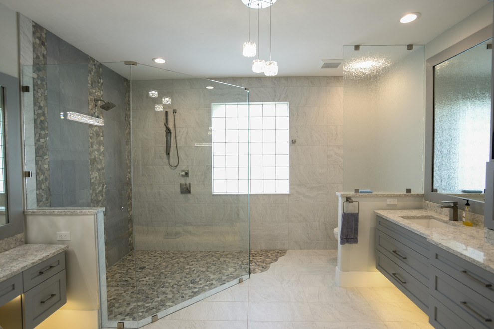 This is an example of a large contemporary master bathroom in Other with shaker cabinets, grey cabinets, a double shower, a two-piece toilet, white tile, porcelain tile, grey walls, porcelain floors, an undermount sink, quartzite benchtops, grey floor, a hinged shower door and grey benchtops.