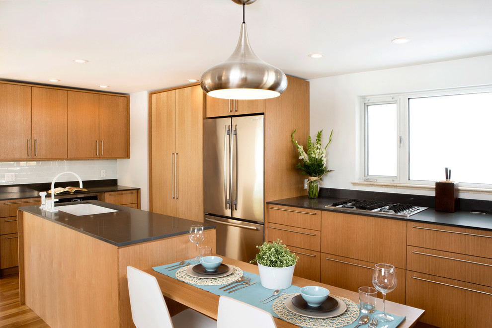 Contemporary l-shaped eat-in kitchen in Denver with an undermount sink, flat-panel cabinets, light wood cabinets, quartz benchtops, white splashback, glass tile splashback and stainless steel appliances.