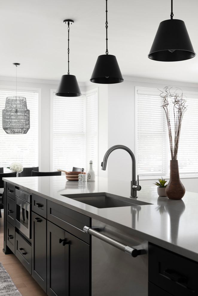Mid-sized transitional galley light wood floor open concept kitchen photo in Chicago with an undermount sink, shaker cabinets, white cabinets, quartz countertops, white backsplash, ceramic backsplash, stainless steel appliances, an island and gray countertops