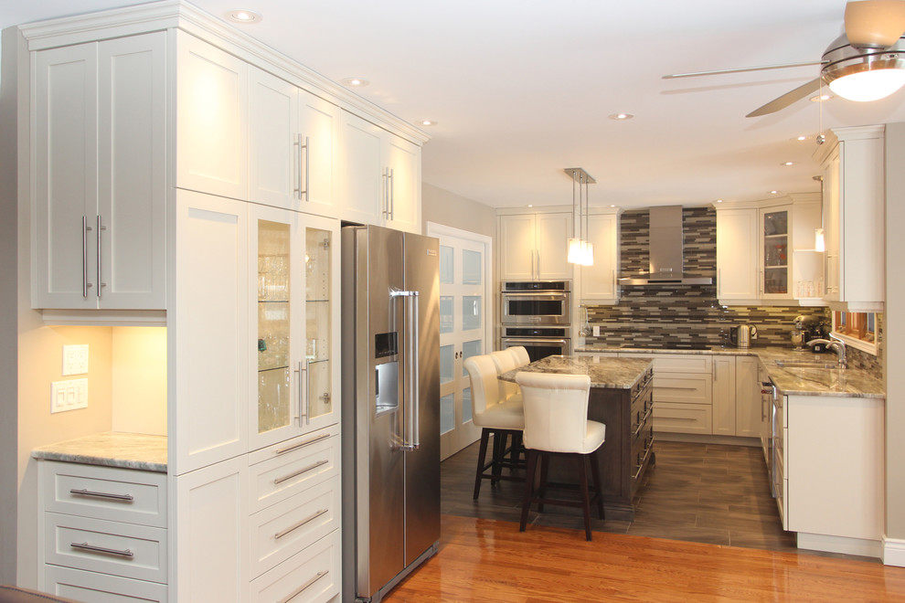 Small transitional l-shaped dark wood floor and brown floor eat-in kitchen photo with white cabinets, granite countertops, multicolored backsplash, glass tile backsplash, stainless steel appliances, an island and shaker cabinets