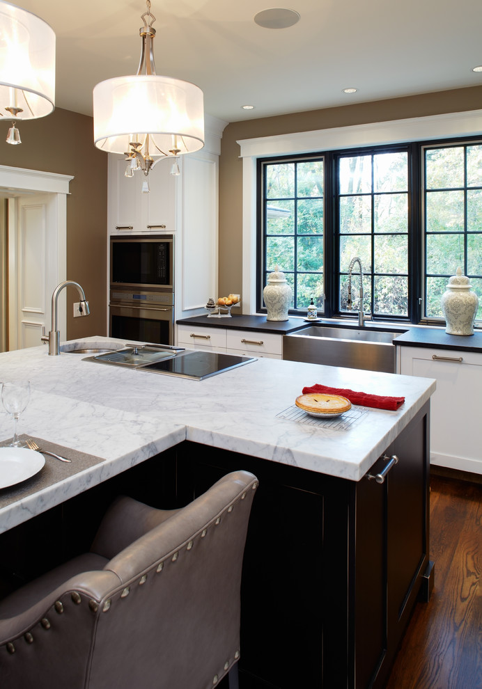 This is an example of a large traditional l-shaped separate kitchen in Philadelphia with a farmhouse sink, shaker cabinets, white cabinets, marble benchtops, white splashback, subway tile splashback, panelled appliances, dark hardwood floors and with island.