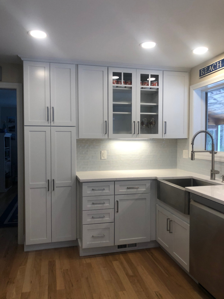 Inspiration for a mid-sized beach style u-shaped eat-in kitchen in Portland Maine with a farmhouse sink, shaker cabinets, white cabinets, soapstone benchtops, blue splashback, mosaic tile splashback, stainless steel appliances, medium hardwood floors, no island, multi-coloured floor and white benchtop.