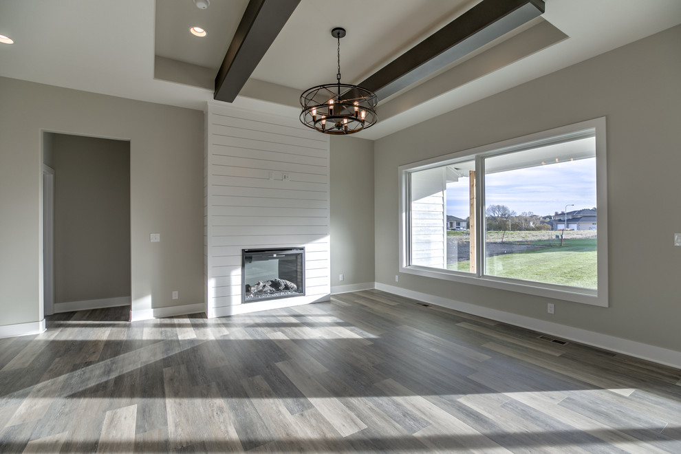 This is an example of a country open concept family room in Omaha with a standard fireplace, a wood fireplace surround and a wall-mounted tv.