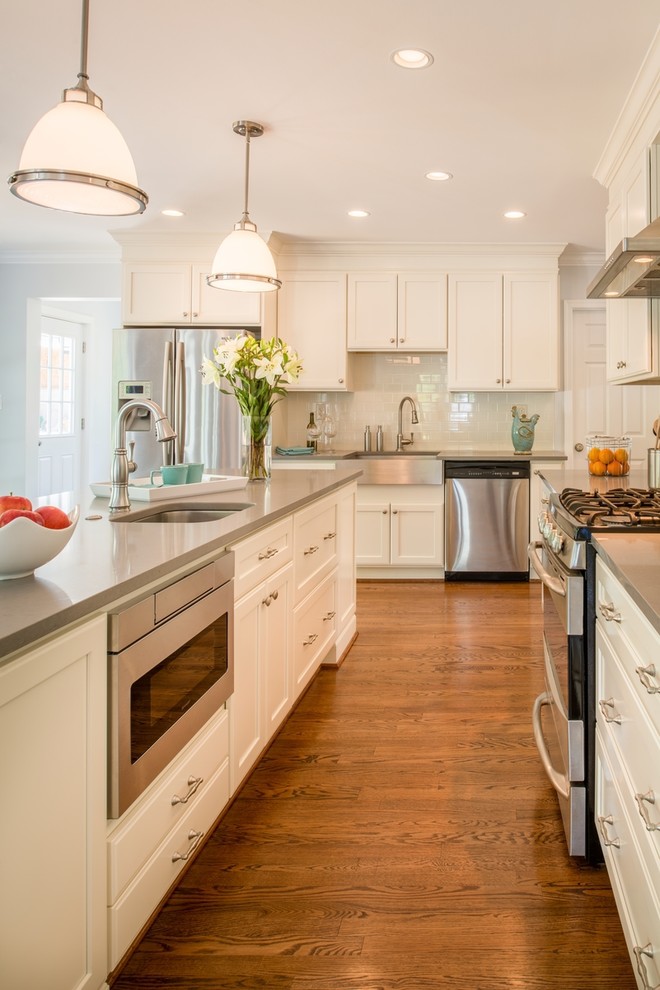 Inspiration for a transitional u-shaped kitchen in DC Metro with a farmhouse sink, recessed-panel cabinets, medium hardwood floors, with island and white cabinets.