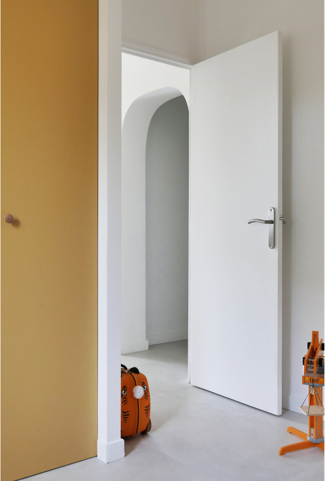 Lantlig inredning av ett mellanstort könsneutralt barnrum kombinerat med lekrum, med gula väggar, klinkergolv i keramik och grått golv
