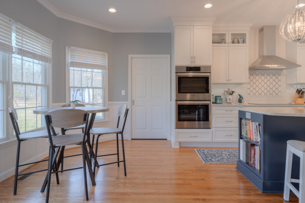 Eat-in kitchen - mid-sized transitional galley medium tone wood floor eat-in kitchen idea with an undermount sink, flat-panel cabinets, white cabinets, quartz countertops, white backsplash, subway tile backsplash, stainless steel appliances, an island and white countertops