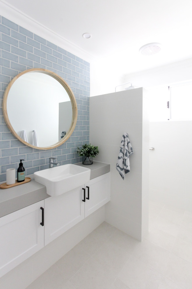 This is an example of a mid-sized beach style 3/4 bathroom in Perth with shaker cabinets, white cabinets, gray tile, subway tile, white walls, a vessel sink, white floor, grey benchtops and a floating vanity.