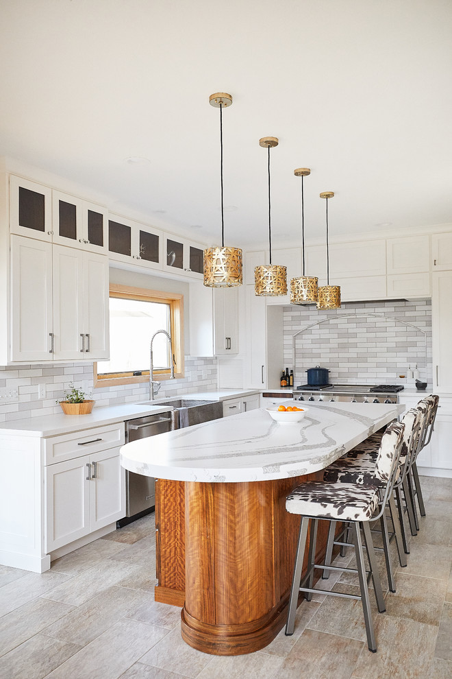 Large transitional u-shaped kitchen in Minneapolis with a farmhouse sink, shaker cabinets, white cabinets, quartz benchtops, grey splashback, subway tile splashback, stainless steel appliances, ceramic floors, with island, grey floor and white benchtop.