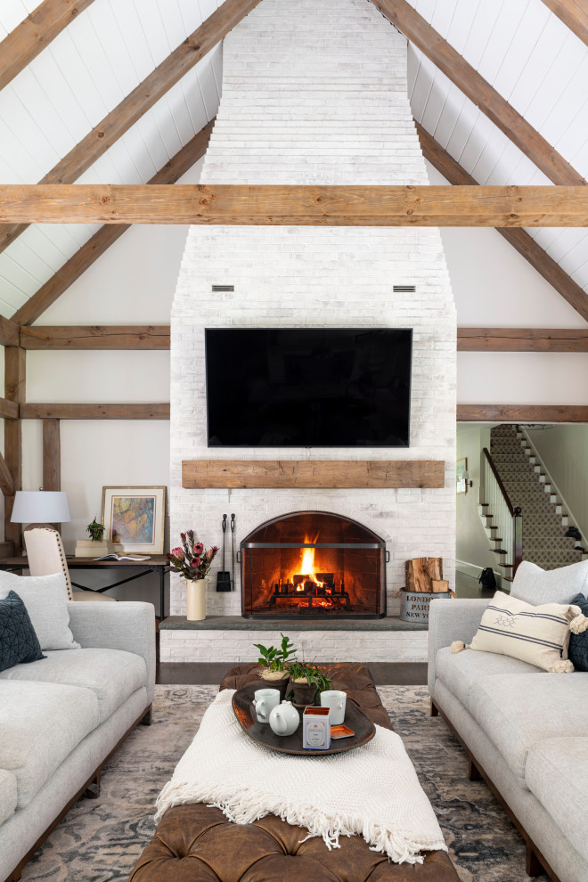Example of a huge open concept dark wood floor, brown floor and exposed beam family room design in Boston with white walls, a standard fireplace, a brick fireplace and a wall-mounted tv