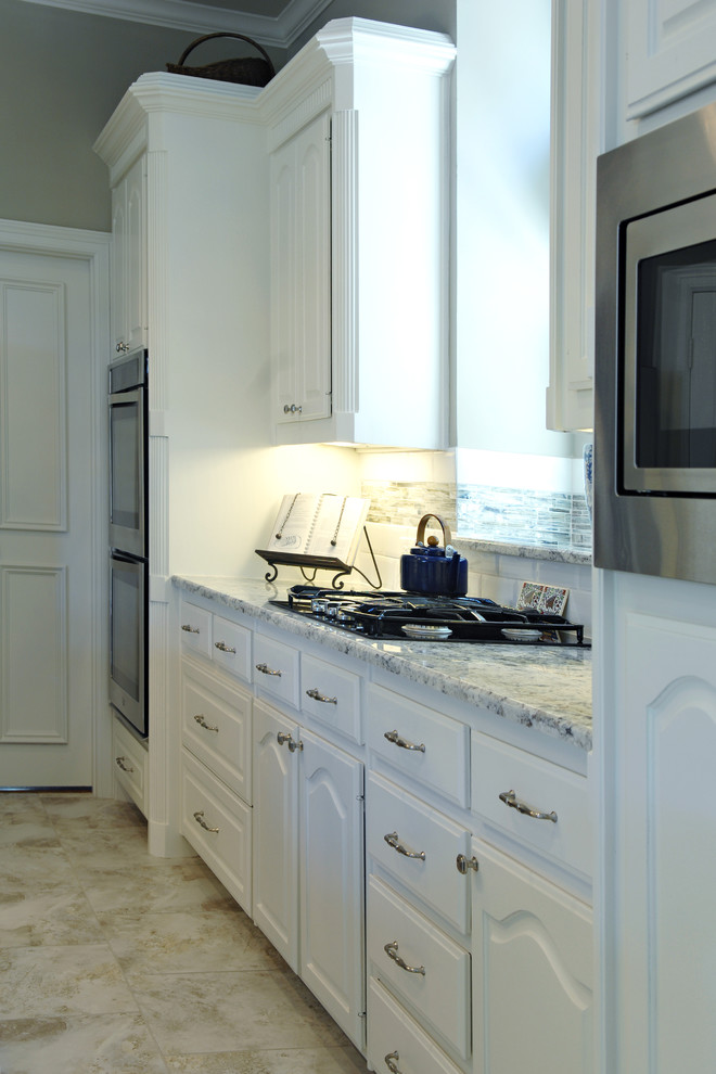 Eat-in kitchen - large transitional u-shaped eat-in kitchen idea in Dallas with white cabinets, granite countertops, multicolored backsplash, matchstick tile backsplash, stainless steel appliances and an island